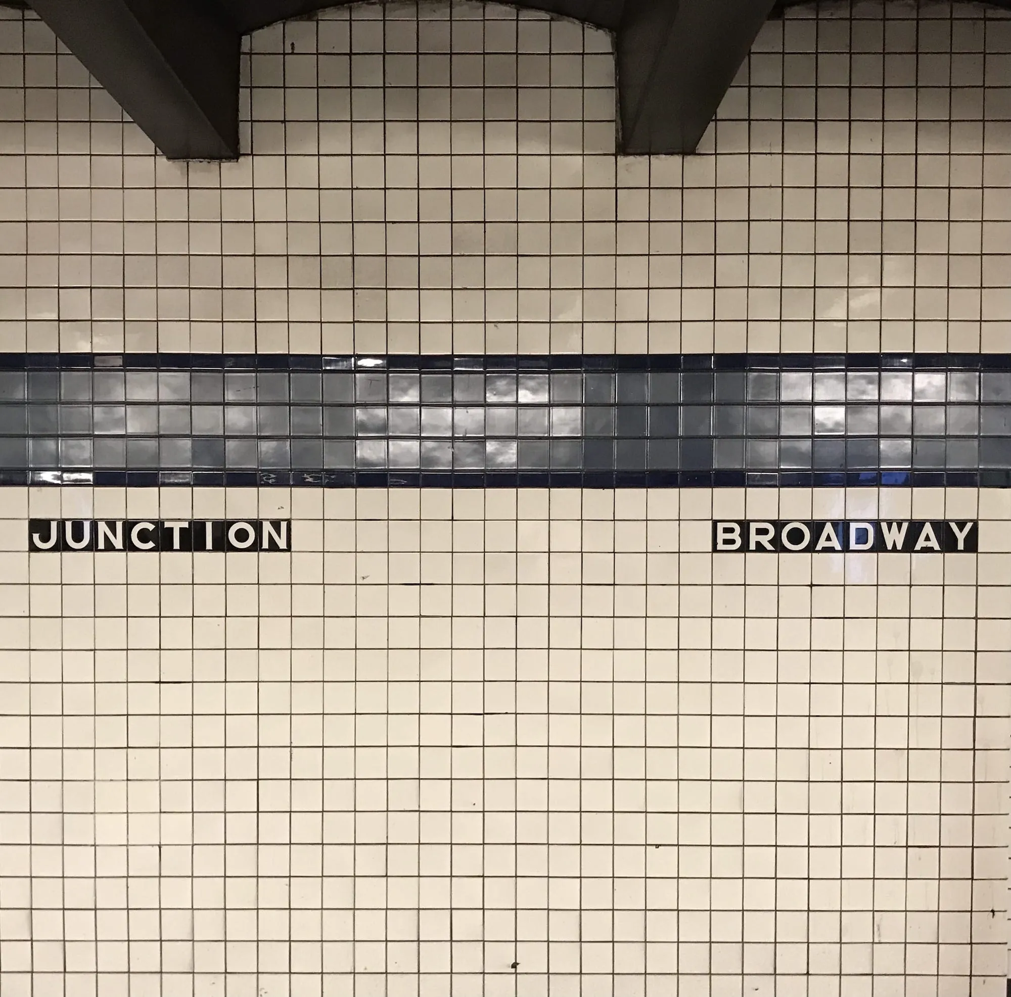 Tiled subway wall with the labels 'junction' and 'broadway'